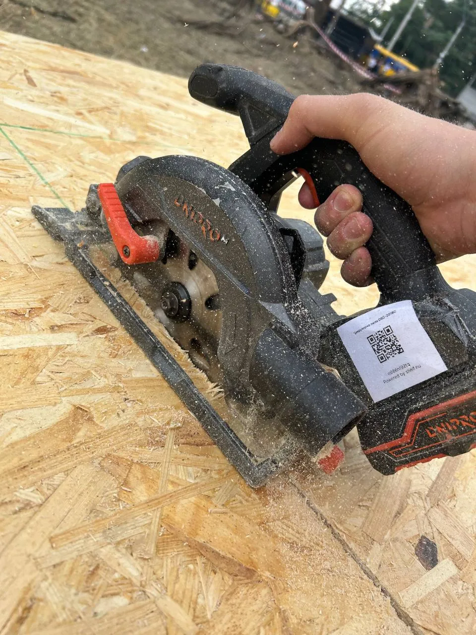 A circular saw with its Shelf QR label cutting an OSB panel on site, July 2026