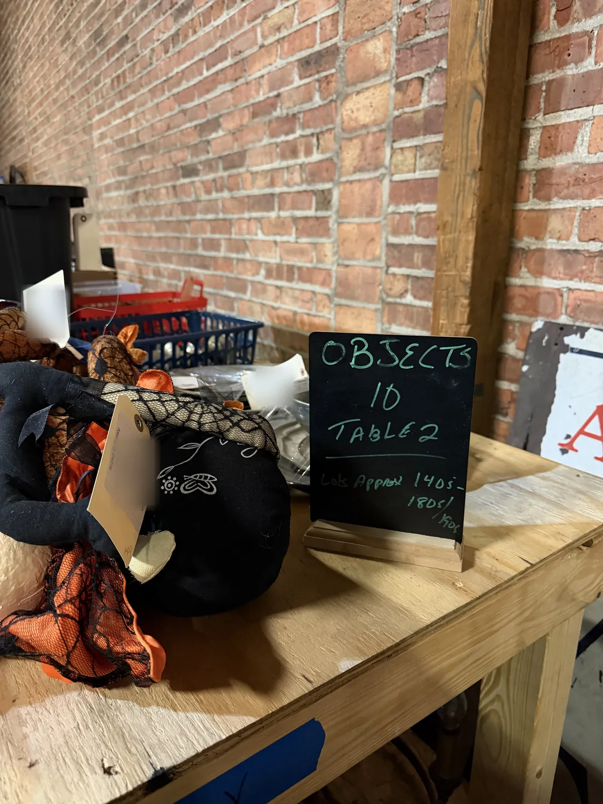 Chalkboard sign on a rolling table reading "Objects 10, Table 2, Lots approx 140s to 190s", with tagged lots beside it